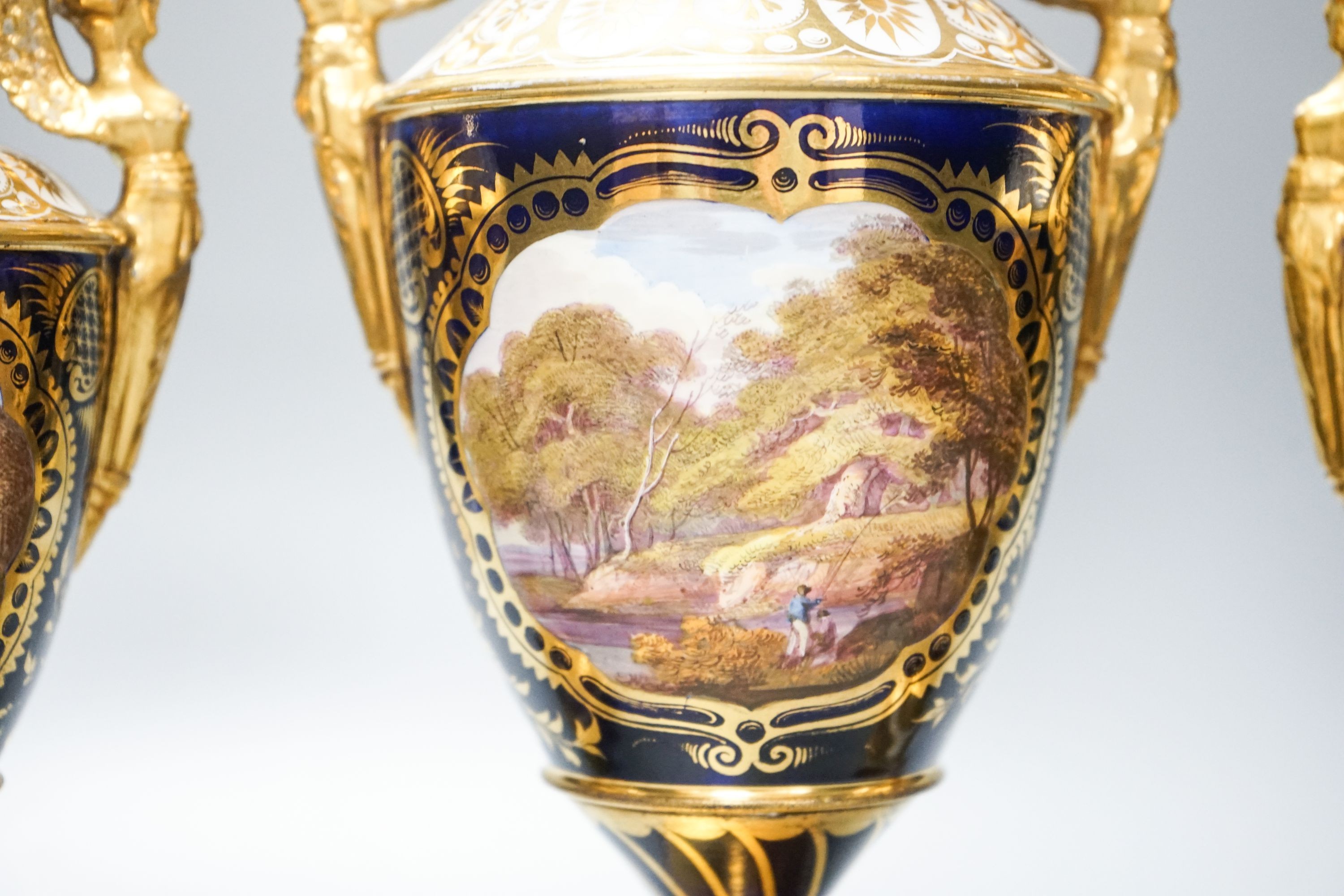 A garniture of three early 19th century English porcelain vases, c.1815-20, each painted with topographical views, tallest 26cm